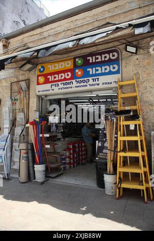 Échelles et balais près d'une façade de magasin vendant des outils et des appareils de construction dans le marché Machane Yehuda à Jérusalem Banque D'Images