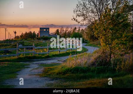 Un chemin sinueux menant au coucher du soleil à travers une tour d'observation faite d'un ancien bâtiment. Sentier de randonnée à Paljassaare, Tallinn, Estonie. Banque D'Images