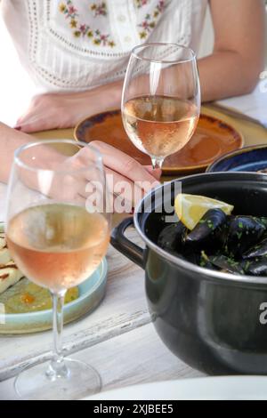 Jeune femme enjoigniyng dîner dans le restaurant méditerranéen. Verre de rose et divers plats servis sur la table. Banque D'Images