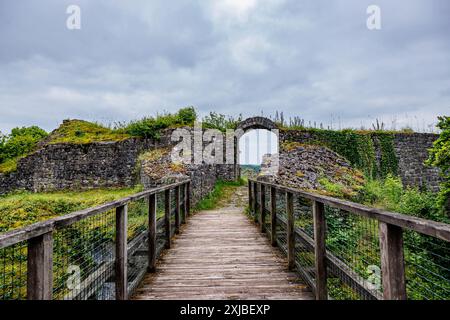 Pont en bois menant à une porte voûtée au château de Logne, mur de pierre usé par le temps contre ciel couvert de nuages gris, jour nuageux à Ferrières, Belgique Banque D'Images