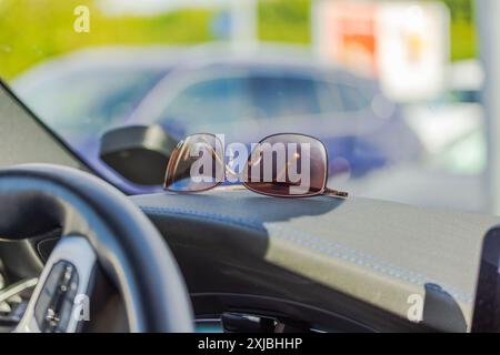 Vue rapprochée de lunettes de soleil couchées sur le tableau de bord du côté conducteur de la voiture. Banque D'Images