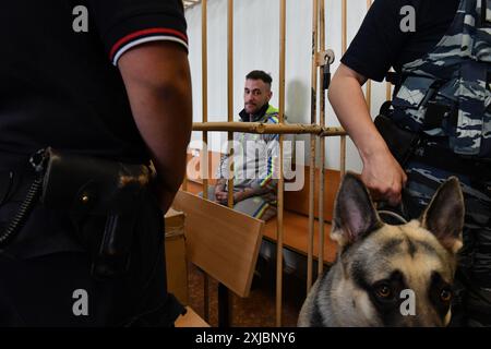 Pétersbourg, Russie. 17 juillet 2024. Le citoyen allemand Patrick Schobel, soupçonné de trafic de drogue, est assis dans la cage de l'accusé dans une salle d'audience de Saint-Pétersbourg. Patrick Schobel a été arrêté à l’aéroport de Pulkovo pour avoir transporté des bonbons gommeux contenant du cannabis. Crédit : SOPA images Limited/Alamy Live News Banque D'Images