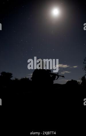 Un soldat affecté au 190e bataillon du génie, 101e commandement des troupes, garde nationale de l'armée de Porto Rico, s'agenouille lors d'une marche nocturne au Camp Santiago joint Training Center, Salinas, Porto Rico, le 15 juillet 2024. La familiarité avec l’équipement NVG pendant un ruck est cruciale pour que les soldats maintiennent une conscience de la situation et effectuent des tâches avec précision dans l’obscurité, améliorant ainsi l’efficacité opérationnelle et la sécurité. (Photo de la Garde nationale de l'armée américaine par le SPC Felix Ortiz Rivera) Banque D'Images