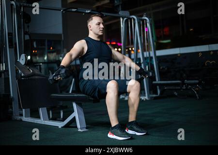 Homme s'entraînant sur la machine de pulldown Lat dans le gymnase Banque D'Images