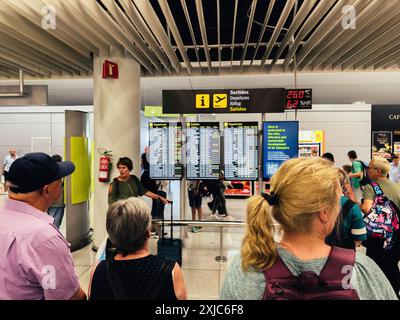 Palma, Espagne - 11 juillet 2024 : les voyageurs vérifient les informations de départ sur les écrans numériques de l'aéroport de PMI, avec un environnement de terminal très fréquenté avec divers passagers et panneaux Banque D'Images