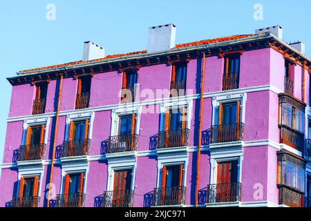 Bâtiment rose avec balcons et fenêtres. Maison peinte en rose ajoutant une touche de charme vintage Banque D'Images