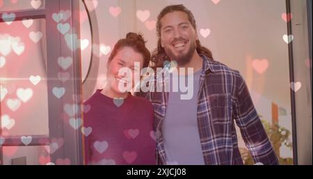 Image de cœurs sur un couple diversifié heureux à la maison Banque D'Images