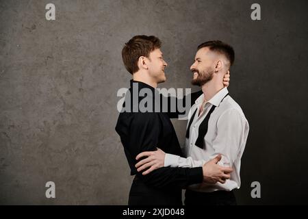 Deux hommes en costumes, embrassant, sur un fond concret. Banque D'Images