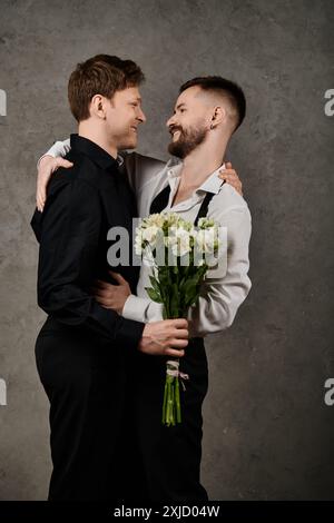 Deux hommes en costume embrassent, l'un tenant des fleurs, regardant avec amour. Banque D'Images