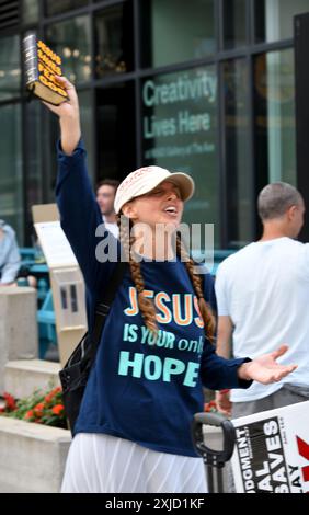 Milwaukee, Wisconsin, États-Unis. 17 juillet 2024. Une femme de Floride qui a donné son nom seulement comme REINA, chante des chansons religieuses près de l'entrée de la zone de sécurité le troisième jour de la Convention nationale républicaine au Forum Fiserv à Milwaukee, Wisconsin mercredi 17 juillet 2024. (Crédit image : © Mark Hertzberg/ZUMA Press Wire) USAGE ÉDITORIAL SEULEMENT! Non destiné à UN USAGE commercial ! Banque D'Images