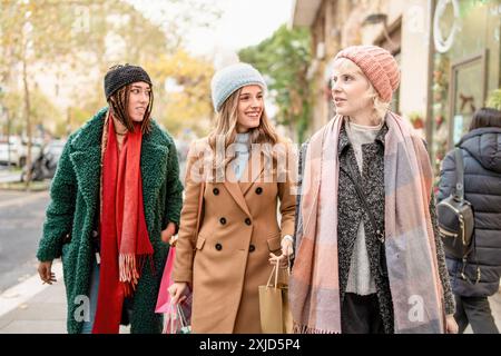 Groupe de femmes diverses se promenant dans la ville à l'automne. Amis de différentes ethnies portant des tenues d'automne à la mode, portant des sacs à provisions. Scène d Banque D'Images