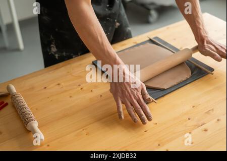 Gros plan des mains de potier qui déroulent de l'argile. Banque D'Images