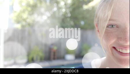 Image de taches lumineuses sur un demi-portrait d'adolescente caucasienne heureuse souriant dans le jardin Banque D'Images