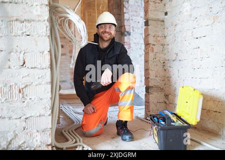 Portrait de jeune ingénieur électrique souriant sur le chantier de construction pendant le processus d'installation. Banque D'Images