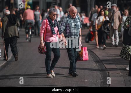 Cambridge, Royaume-Uni - 08 octobre 2023 : un couple âgé marche main dans la main dans une rue pavée à Cambridge, Royaume-Uni. Ils semblent profiter d'un leisu Banque D'Images