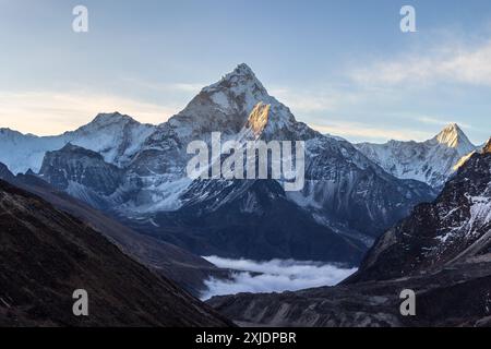 Montagne AMA Dablam au lever du soleil et ciel bleu. Le soleil illumine les pentes. Montagnes de l'Himalaya, Népal. Banque D'Images