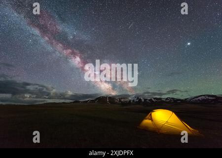 Voie lactée sur Starry Night Sky avec Airglow et tente jaune luisante. Concept de camping Banque D'Images