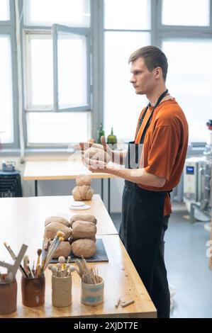 Potter pétrit l'argile avant de l'utiliser dans l'atelier. Photo verticale. Banque D'Images