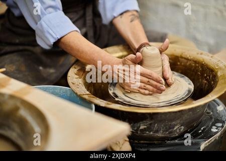 Gros plan d'une main de femme façonnant de l'argile sur une roue de poterie. Banque D'Images