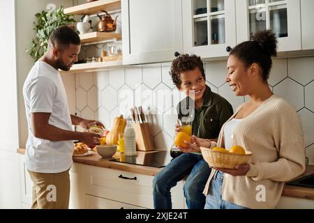 Famille diversifiée préparant joyeusement la nourriture ensemble dans la cuisine. Banque D'Images