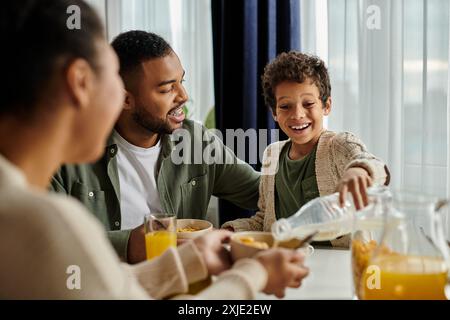 La famille afro-américaine aime le jus d'orange à une table. Banque D'Images