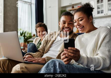 Homme et femme engrossés dans le téléphone portable alors qu'ils étaient assis sur le canapé, avec leur fils. Banque D'Images