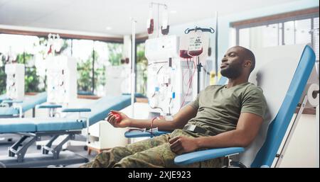 Un soldat de l'armée mâle noir donne du sang pour des camarades blessés à l'hôpital militaire. Brave troupe africaine pressant la balle rouge en forme de cœur pour pomper le sang à travers la tubulure dans le sac. Don pour les hommes en service Banque D'Images