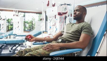 Un soldat de l'armée mâle noir donne du sang pour des camarades blessés à l'hôpital militaire. Troupe africaine pressant la balle rouge en forme de cœur pour pomper le sang à travers la tubulure dans le sac. Don pour les hommes en service Banque D'Images