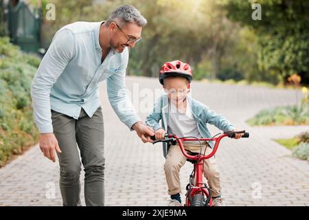 Père, fils et apprendre à faire du vélo en plein air, soutien aux parents et activité de formation pour les enfants. Papa, garçon et enseigner le cyclisme dehors ou aider Banque D'Images