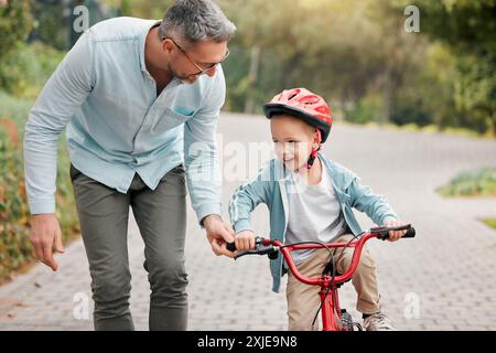 Père, fils et apprendre à faire du vélo en plein air, soutien aux parents et activité de formation pour les enfants. Papa, garçon et enseigner le vélo à l'extérieur ou aider pour l'enfant Banque D'Images