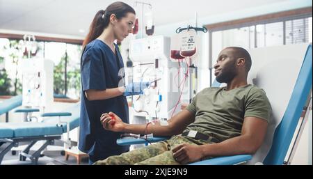 Une infirmière caucasienne qui reçoit un don de sang du soldat de l'armée noire à l'hôpital militaire. Homme afro-américain pressant la balle en forme de coeur pour pomper le sang dans le sac. Don de troupes aux camarades blessés. Banque D'Images