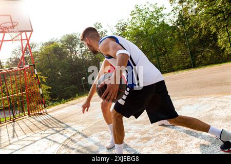 Deux amis masculins jouant au basket-ball sur le terrain en plein air. Banque D'Images