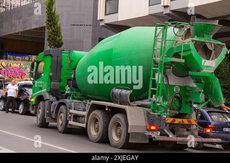 Tbilissi, Géorgie - 20 JUIN 2024 : camion de mélange de ciment déchargeant devant un nouveau bâtiment résidentiel en construction dans le centre de Tbilissi, Géorgie. Banque D'Images