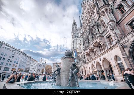 Munich, Allemagne - date inconnue : la Frauenkirche, ou nouvel hôtel de ville de Munich, domine une fontaine et une foule de gens dans la Marienplatz. Banque D'Images