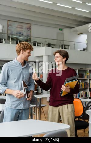 Deux jeunes hommes se sont pris dans la conversation à une bibliothèque. Banque D'Images