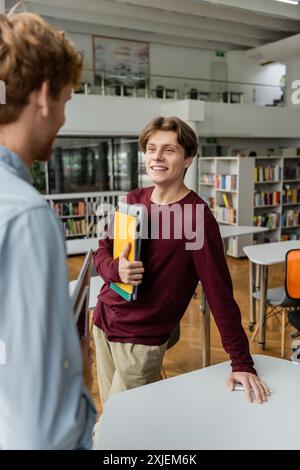 Un homme se tient à une table dans une bibliothèque à côté de son ami. Banque D'Images