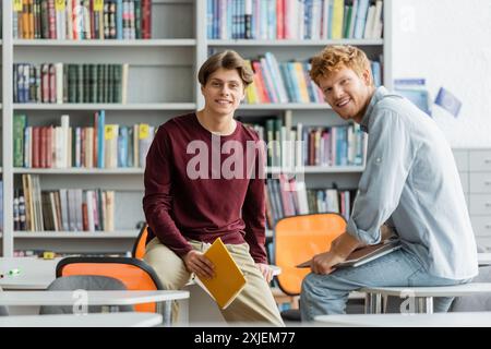 Deux jeunes hommes se sont engagés dans des activités savantes au milieu d'une bibliothèque. Banque D'Images