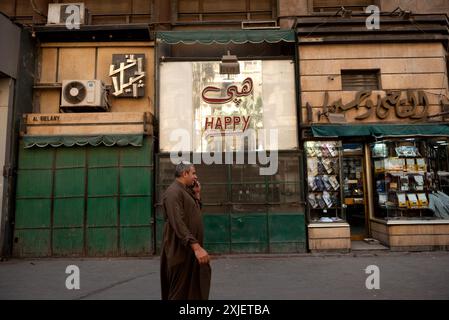 Le Caire, Égypte. 14 juin 2024. Scène de rue typique du centre-ville du Caire où un égyptien passe devant les magasins tout en parlant sur un téléphone portable portant des vêtements traditionnels. Crédit : SOPA images Limited/Alamy Live News Banque D'Images