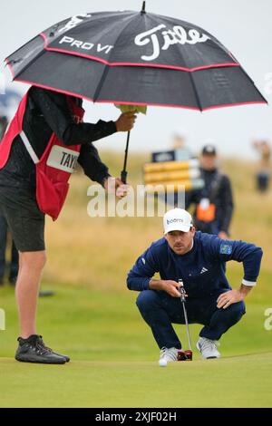 18 juillet 2024 ; Royal Troon Golf Club, Troon, South Ayrshire, Écosse ; Open Championship 1st Round ; le caddy de Nick Taylor abrite son ballon sous de fortes pluies sur le 4th green Banque D'Images