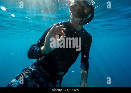 Caucasien homme snorkeler nageant dans les eaux bleues profondes avec masque, tuba, palmes et équipement de natation de garde d'éruption noire Banque D'Images