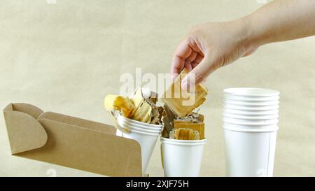 Tasse à café en papier blanc, papier usagé et boîte en carton sur une surface brune, en attente de recyclage. Encourage le recyclage des déchets, sauver la Terre et conserver Banque D'Images