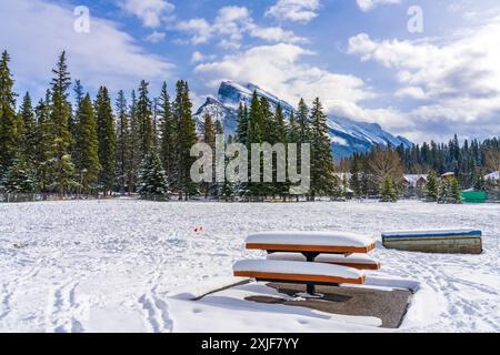 Banc en bois enneigé dans le parc de loisirs de Banff en hiver enneigé. Parc national Banff, Rocheuses canadiennes, Alberta, Canada. Banque D'Images