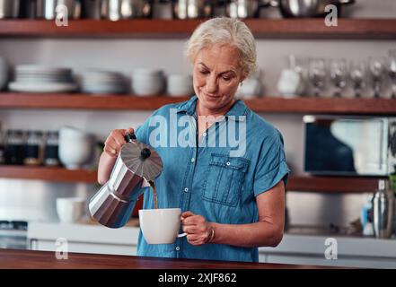 Femme, café et moka pot dans la cuisine pour fort, riche et saveur tout en se relaxant le matin le week-end. Senior, retraite et latte ou espresso Banque D'Images