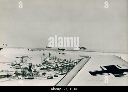 Une photographie montre une formation d'avions Junkers Ju 87 (Stuka) retournant à leur base à basse altitude après avoir terminé une mission. Les avions, camouflés en blanc, volent dans des conditions enneigées. Prise lors de l'opération Barbarossa en 1941, cette image met en évidence les efforts continus de la Luftwaffe alors que les forces allemandes avançaient contre les positions soviétiques sur le front de l'est. Banque D'Images