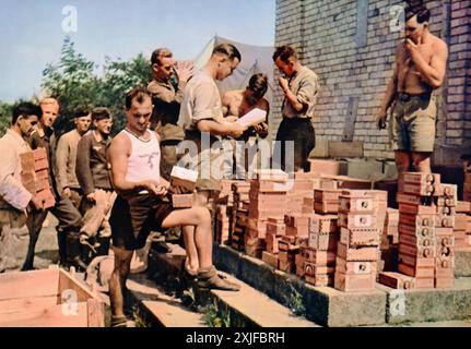 Une photographie en couleur montre des soldats allemands organisant et distribuant des marchandises commerciales nouvellement arrivées pendant la seconde Guerre mondiale. Prise en 1941 lors de l'opération Barbarossa, cette image met en évidence les efforts logistiques nécessaires pour soutenir les forces allemandes qui avancent alors qu'elles traversent le territoire soviétique sur le front de l'est. Banque D'Images