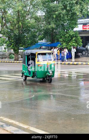 Pousse-pousse auto à New Delhi, en Inde, par un jour de pluie, conduisant à travers les rues humides et les scènes urbaines Banque D'Images