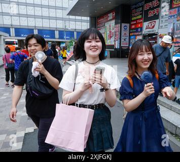 CHALEUR À TOKYO FILLES UTILISANT DES VENTILATEURS PORTABLES Banque D'Images