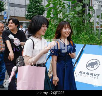 CHALEUR À TOKYO FILLES UTILISANT DES VENTILATEURS PORTABLES Banque D'Images