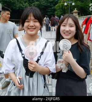 CHALEUR À TOKYO FILLES UTILISANT DES VENTILATEURS PORTABLES Banque D'Images