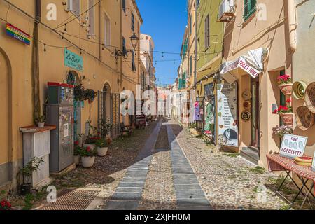 ALGHERO, ITALIE - 4 JUILLET 2024 : rue pittoresque médiévale, typique sarde, avec de petites boutiques de souvenirs traditionnelles. Banque D'Images